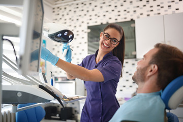 Smiling dentist working with patient in dental clinic