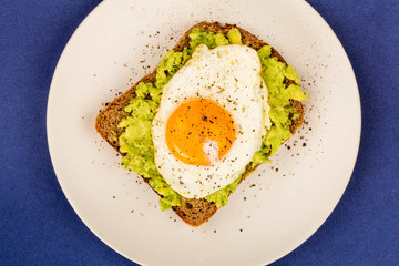 Fried Egg Sunny Side Up on Crushed Avocado And Rye Bread Open Faced Sandwich