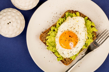 Fried Egg Sunny Side Up on Crushed Avocado And Rye Bread Open Faced Sandwich