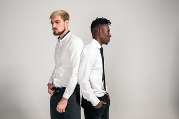 Friends. Two guys in white shirts and dark pants posing in the studio on a white background