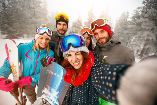 Group of happy friends having fun Snowboarders and skiers making selfie