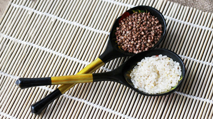 Dry white colored rice and buckwheat in wooden spoon