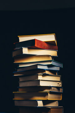 Tower Of Old Multi-colored Books On A Black Background. Concept Of Education And Knowledge