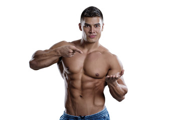 Fototapeta premium A smiling male bodybuilder points to his open palm. The picture is suitable for advertising sports goods and services.