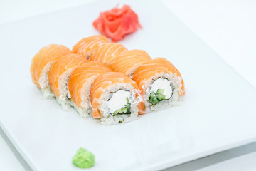 Philadelphia roll sushi with rice, nori, wasabi, soy sauce, pickled ginger, cheese, cucumber, salmon. Sushi