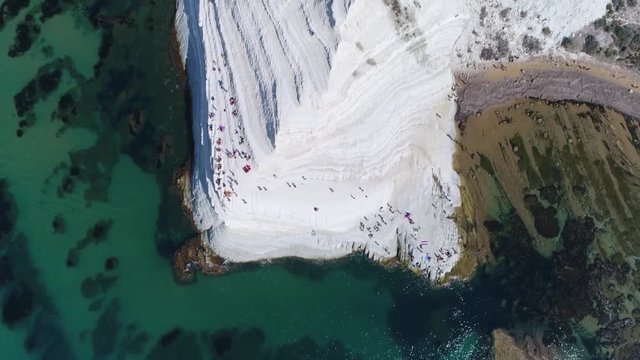 Aerial top down view of Scala dei Turchi in english Stair of the Turks and sunbathing people this rocky cliff on coast of Realmonte in southern Sicily Italy has become a popular tourist attraction 4k