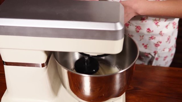 close up shot of an electric mixer, which stirs the dough, the corolla quickly walks in a circle to create a homogeneous mass and whisk the product