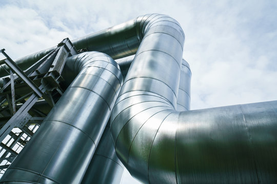 Industrial pipelines on pipe-bridge against blue sky