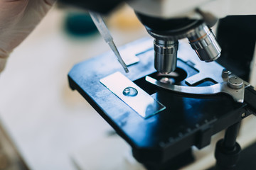 Unrecognizable worker or scientist working with microscope in laboratory