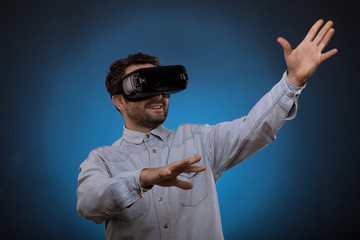 Handsome man wearing future technology VR glasses ,Studio shot, blue backgroun
