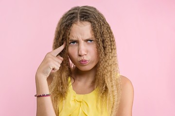 Teenage girl blonde with curly hair frowning, frowning her eyebrow while looking away with placid and thoughtful look.