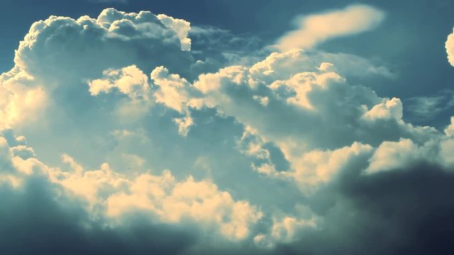 Panning across a dramatic and intense blue sky filled with large white clouds during one bright summer day