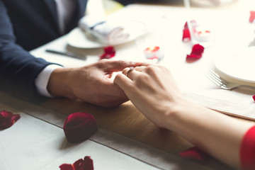 Young couple having romantic dinner in the restaurant wearing a proposal ring close-up
