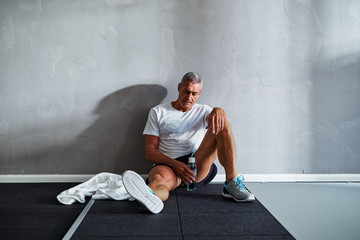 Naklejka premium Tired senior man relaxing after a health club workout