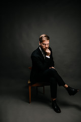 man in suit sits on chair and thinks