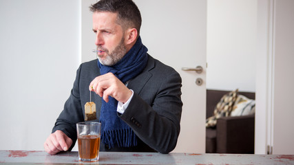 businessman sitting at table with tea und thermometer