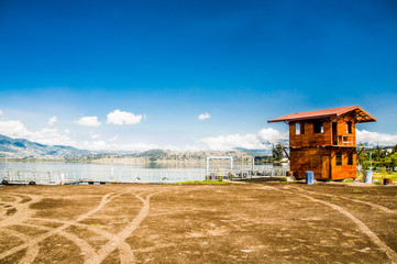 Beautiful view of a wooden hut construction in the border of San Pablo lake in the middle of the valley in a beautiful day with blue sky and some clouds