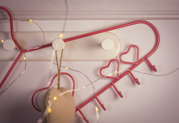 Pink Heart clothes hanger on red background. Valentines day concept
