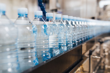 Bottling plant - Water bottling line for processing and bottling pure spring water into blue bottles. Selective focus. 