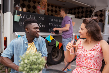 friends with drinks sitting at table at food truck