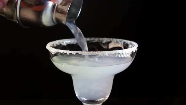 Process Of Serving Margarita Cocktail. Bartender Pouring Alcohol Drink Into A Glass Close-up.