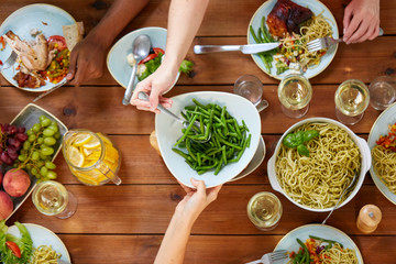 people at table with food eating green beans
