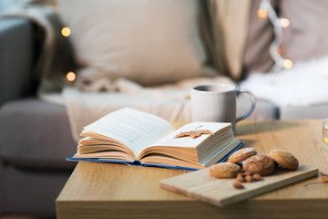 book with autumn leaf, cookies and tea on table