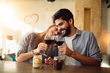 Romantic couple cheers with red wine and celebrating Valentine's day.