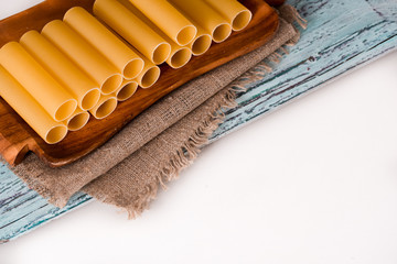 Italian pasta cannelloni. Raw tube for stuffing stuffing surrounded by ingredients for cooking,...