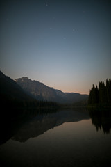 mountain lake reflects in the sunset with trees