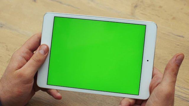 Man using horizontal tablet with green screen. Close-up shot of man's hands with tablet. Chroma key. Close up. Horizontal