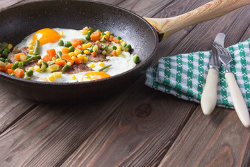 Pan of fried eggs with bacon, mexican vegetable and bread