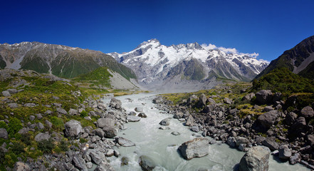 Beautiful natural landscape. Rocks, river and snowy mountains in the background. Walking the Hooker Valley Track, Mount Cook, New Zealand. Enjoy the summer. Hiking and walking in the nature. 
