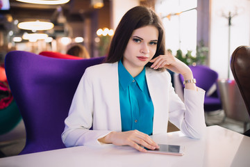 Strict business woman sitting at table in a futuristic cafe