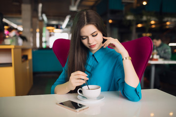 Strict business woman in suit sitting and having break in a futuristic cafe