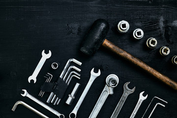 Flat lay of set of tools for car repairing such as wrenches on black wooden background. Top view.