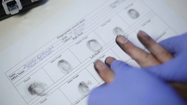 Police officer in exam gloves taking fingerprints from suspect, hands closeup
