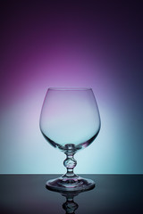 Wineglass on a color background with a black vignette. A tall Wineglass with a thin stalk