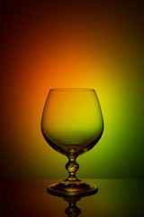 Wineglass on a color background with a black vignette. A tall Wineglass with a thin stalk
