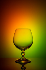 Wineglass on a color background with a black vignette. A tall Wineglass with a thin stalk