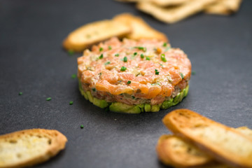 Salmon tartare is made with chopped fresh raw salmon fish, avocado, tartar sauce and crackers or bread. This healthy dish is often served as appetizer in fine dining restaurants.