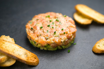 Salmon tartare is made with chopped fresh raw salmon fish, avocado, tartar sauce and crackers or bread. This healthy dish is often served as appetizer in fine dining restaurants.