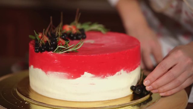 close up shot of the cake that the cook demonstrates, the lady shows a bright cream and fruit ornaments on a dessert that stands on a stand