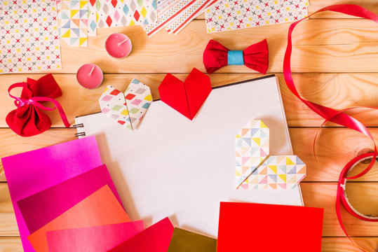 hand made origami paper hearts for valentine's day surrounded by origami paper, candles, gifts
