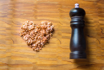 Heart shape in oatmeal with .Pepper grinder on wooden background. Healthy food concept