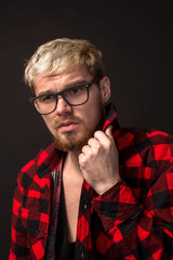 Image of attractive young bearded hipster man wearing glasses dressed in shirt in a cage isolated over black background.
