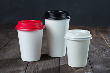 Compilation of three paper cups/ Compilation of three paper cups of coffee to go on the wooden table. Different sizes