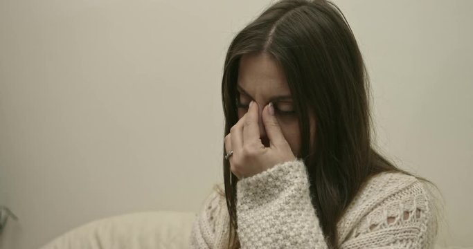 Cute girl caught cold. Sick woman with sinus pain on sofa holding hand on head
