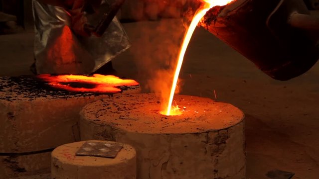 Pouring bronze into mold in foundry