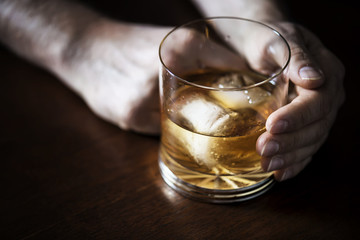 Hand holding a tumbler of old aged rum served chilled